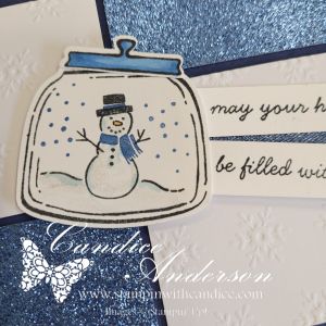 A festive Christmas card featuring a snowman inside a jar with snowflakes in the background and a message that reads, 'may your heart be filled with.'