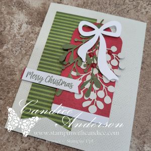 A handmade Christmas card featuring a festive red and green tag design, adorned with a white bow and greenery, and a 'Merry Christmas' sentiment.