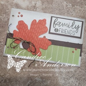 A beautifully designed scrapbook cover featuring an orange autumn leaf and the text 'family & friends.' The background has green striped paper and is accented with a dark brown ribbon and embellishments, creating a warm, inviting autumn theme.