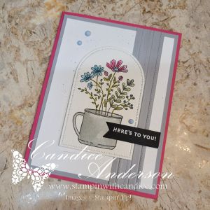 Card featuring a floral arrangement in a cup with a greeting that says 'HERE'S TO YOU!', set against a layered background of gray and pink.
