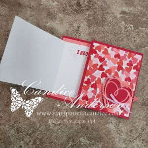 An opened greeting card featuring a colorful design with red and pink hearts on one side and blank white space with the word 'I DO' on the other.