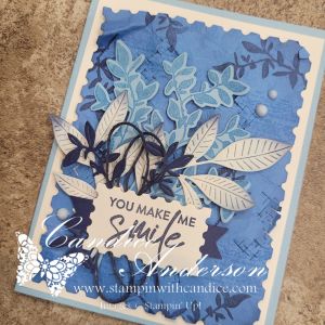 A handmade greeting card featuring a blue color palette with layered leaves and the phrase 'YOU MAKE ME SMILE' prominently displayed in the center.