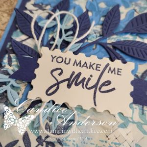 Close-up of a card featuring a decorative design with blue leaves and a central message that says 'You Make Me Smile' in a playful font.