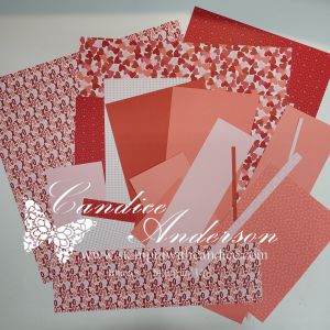 Various sheets of patterned and solid pink and red cardstock arranged on a white surface.