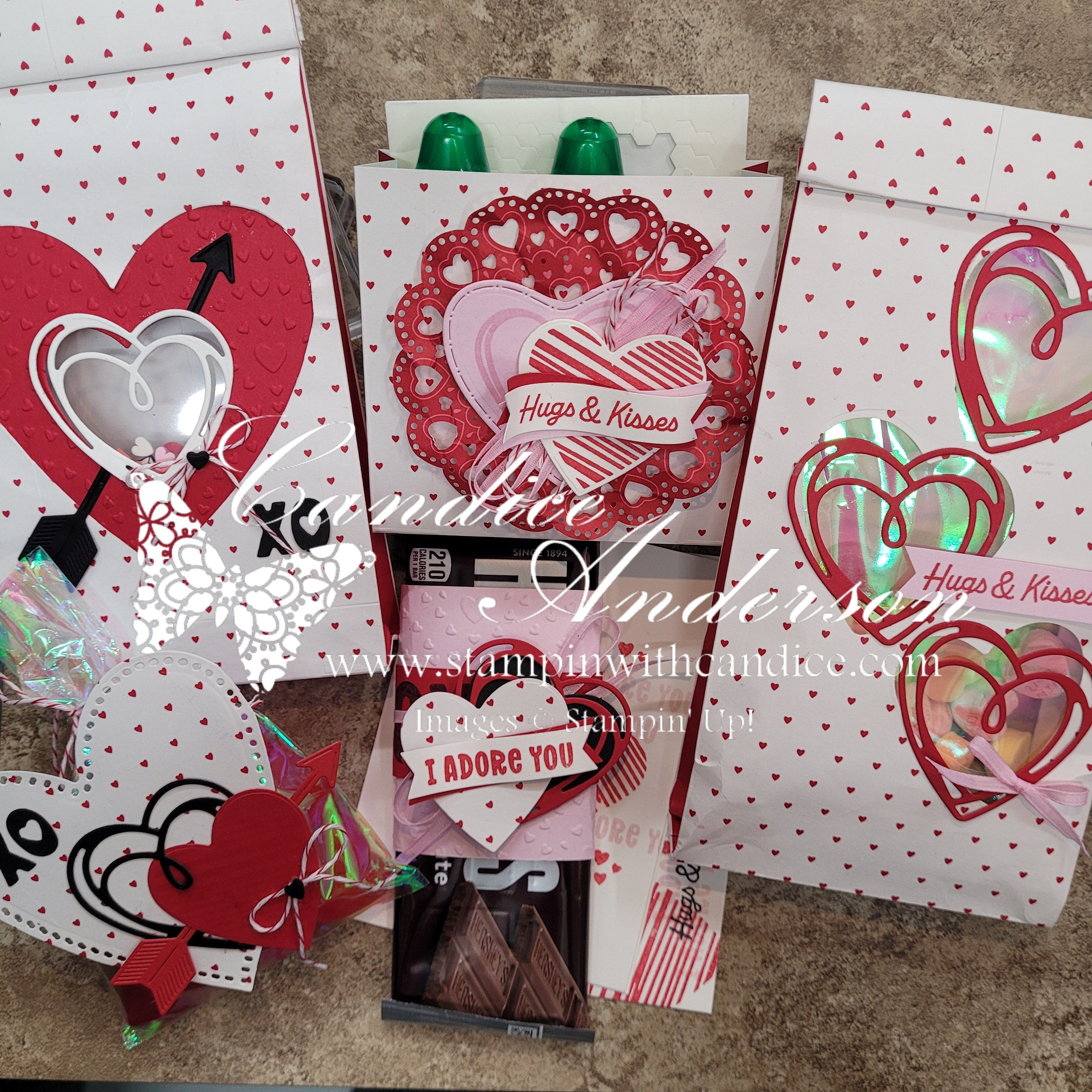 A variety of decorated gift bags with heart designs, featuring messages like 'Hugs & Kisses' and 'I Adore You'. The bags are embellished with red and pink colors, and some contain chocolates and other small gifts.