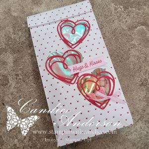 A decorative white bag with red hearts and the phrase 'Hugs & Kisses' printed on a pink ribbon.