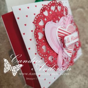 A handmade greeting card featuring layered hearts, a decorative doily, and a mix of red and pink colors, with a white background adorned with small hearts.