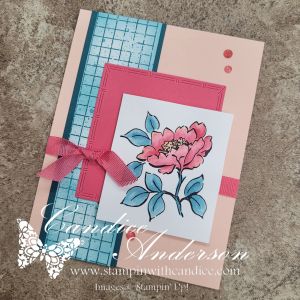 A handmade greeting card featuring a pink floral illustration on a white square, accented with blue and coral geometric patterns and a pink ribbon.