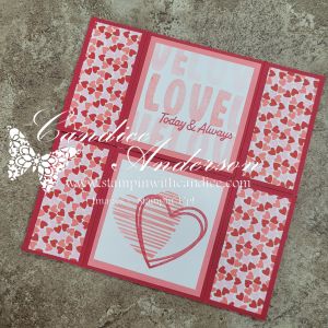 A handmade card featuring a central design with the words 'We Love Today & Always' and a heart graphic, surrounded by patterned borders of small hearts in pink and red.